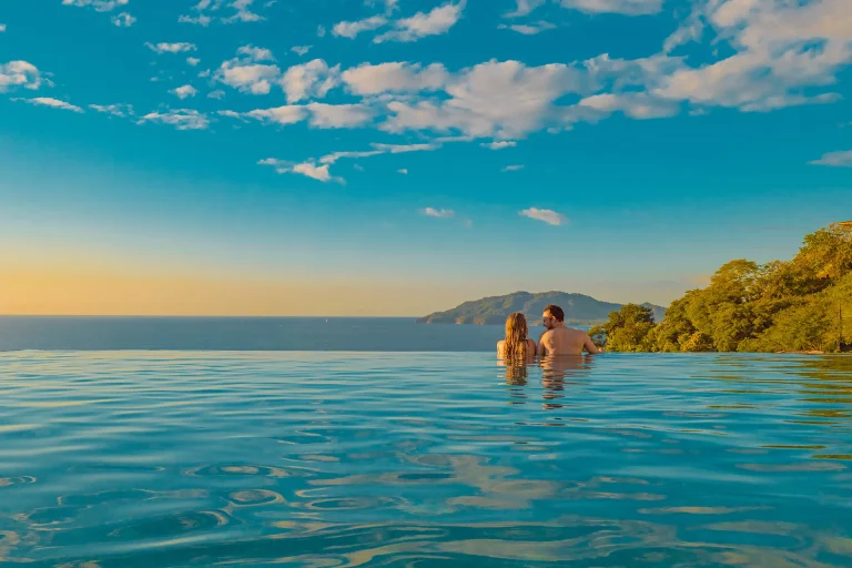 Pareja en la piscina infinita al atardecer_