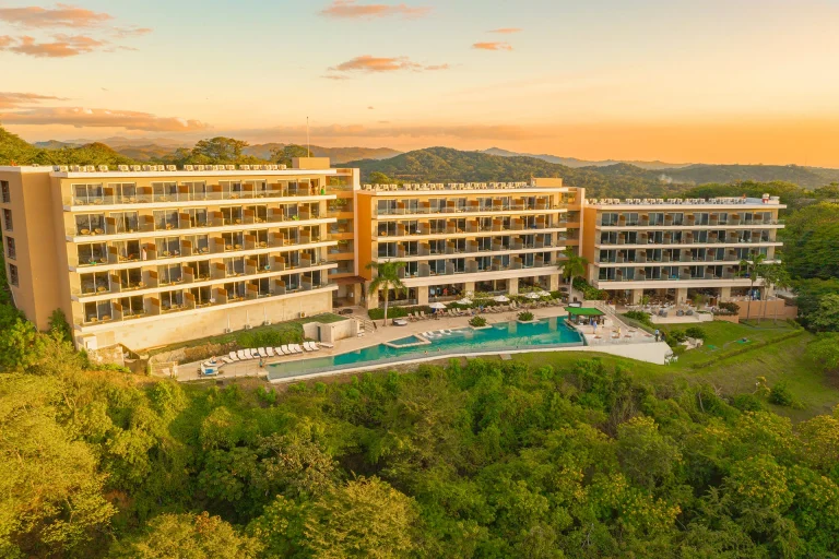 Wyndham Tamarindo al atardecer con piscinas y montañas_