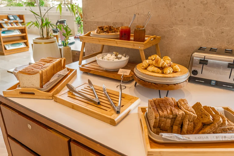 Mesa de panadería con pan, tostadora, mermeladas y bollería para el desayuno